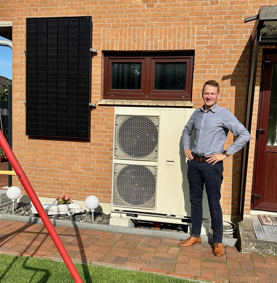 Bauherr vor Einfamilienhaus mit Wärmepumpe