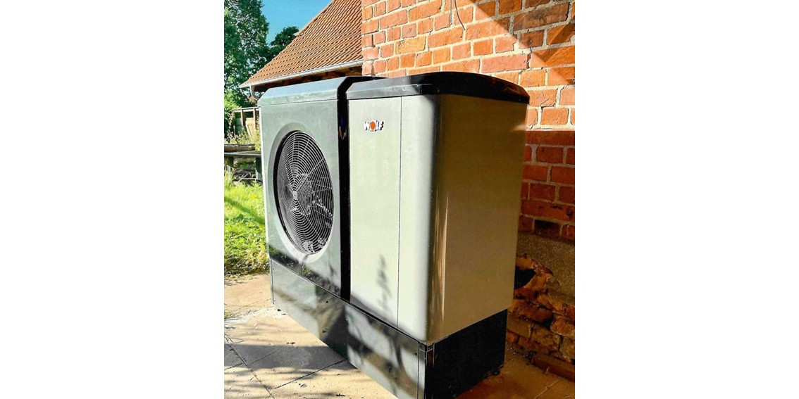 Die Außeneinheit der Wärmepumpe vor einer Klinkerfassade.