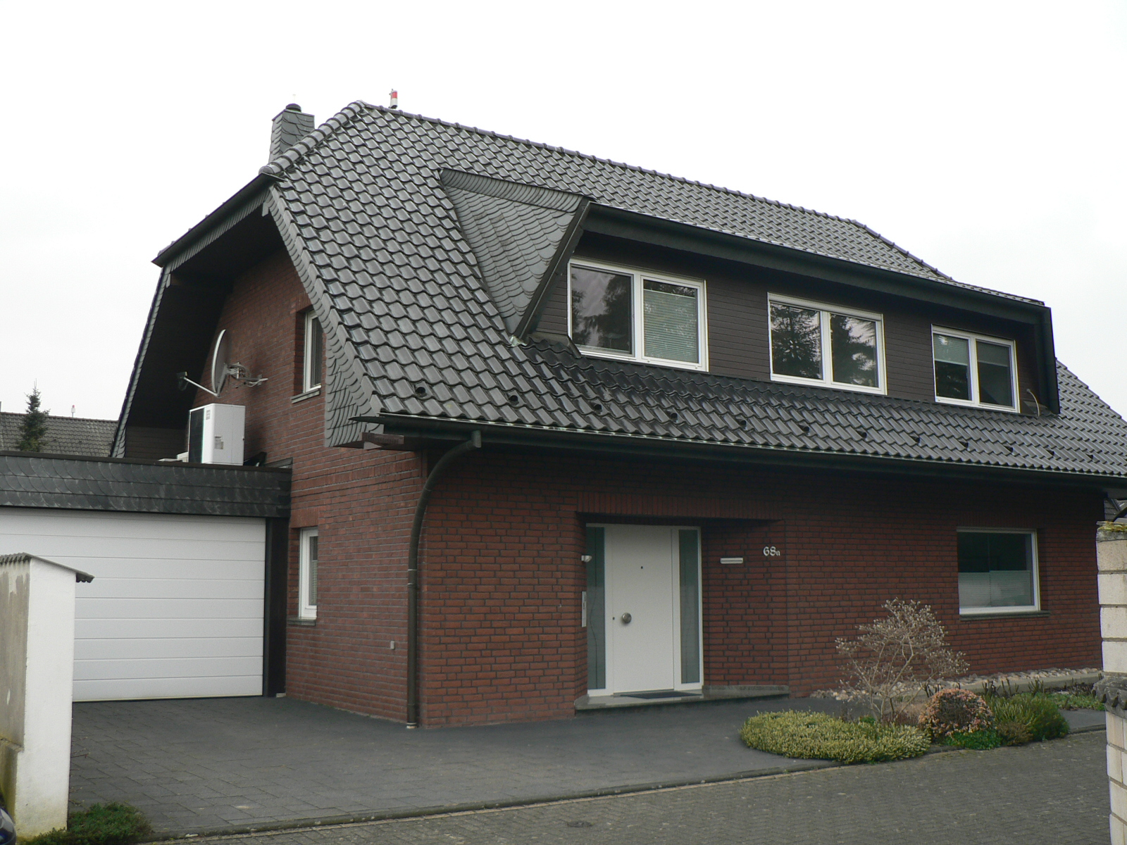 Ein Einfamilienhaus mit angebauter Garage mit Wärmepumpe auf dem Dach.