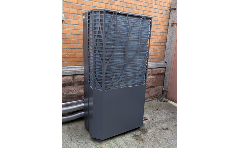 Das Außengerät einer Wärmepumpe vor der geklinkerten Hausfassade.