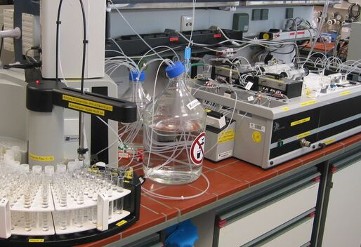 In einem Labor stehen auf einer Arbeitsplatte Analysegeräte und Behälter mit Flüssigkeiten