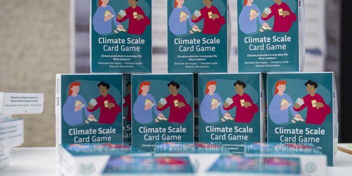Aufsteller mit mehreren Päckchen des Klimawaage-Kartenspiels.