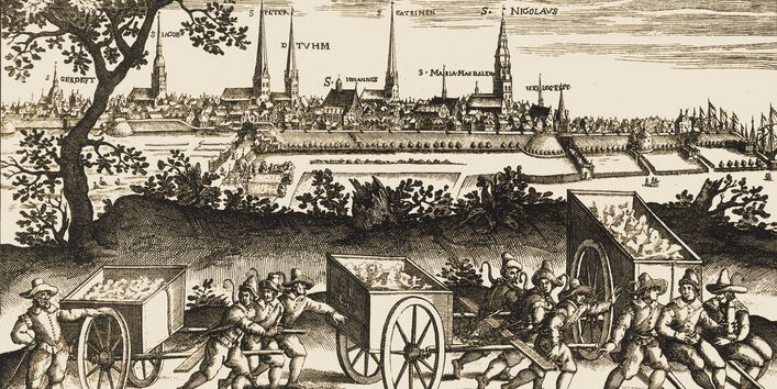 Gefangene transportieren den Müll in großen Handwagen raus aus der Stadt.