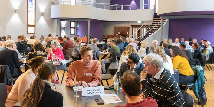 Das Foto zeigt Bürger*innen, die an Gruppentischen diskutieren in einer Beteiligungsveranstaltung zur Deutschen Anpassungsstrategie.