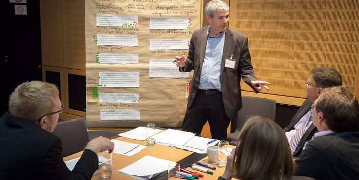 Ein Mann leitet die Gruppenarbeit mit 5 Personen