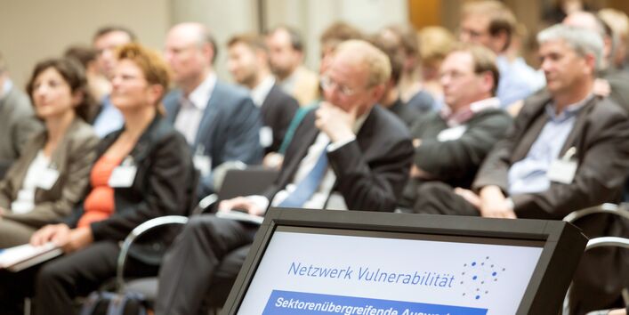 Teilnehmende sitzen und hören einer Präsentation zu