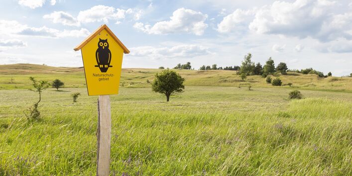 Ein Naturschutzgebiet wird mit einem entsprechenden Schild ausgewiesen.