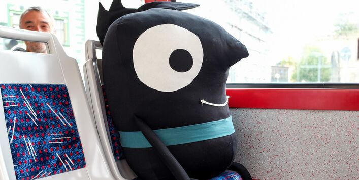 Das EMW-Maskottchen Edgar sitzt als Stoffpuppe in der Tram