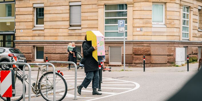 Person läuft mit umgedrehten Periskop über die Straße an einer Stuttgarter Ecke.