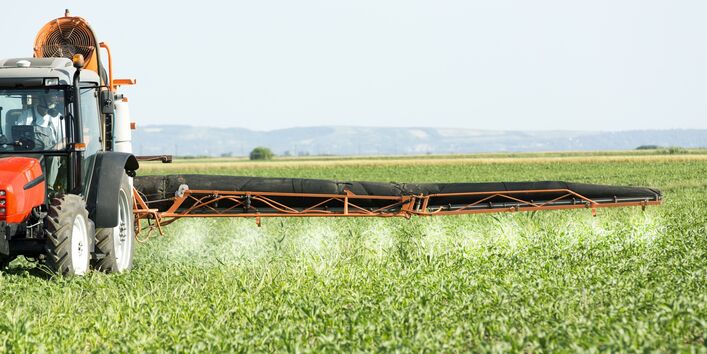 mit einem Traktor werden Pflanzenschutzmittel auf einem Feld ausgebracht