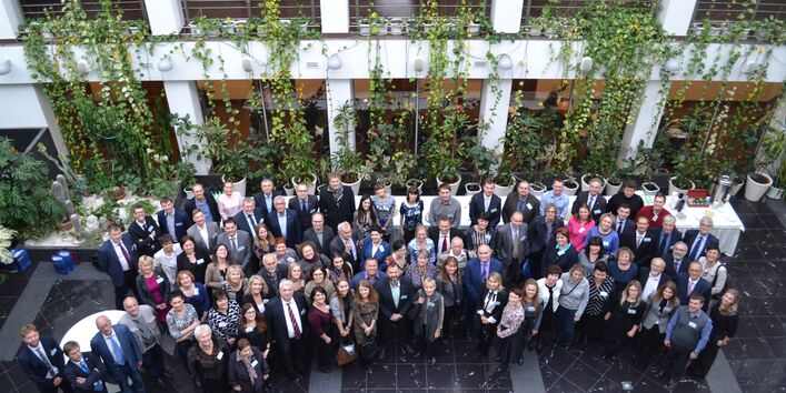 Seen from a higher position, a group of people pose for the camera in a foyer.
