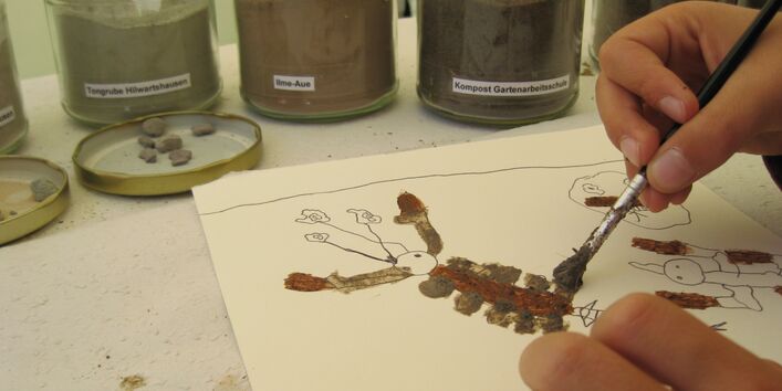 Foto Kind mit Pinsel und Bodenfarben.