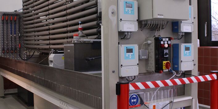 Teststand für Desinfektionsmittel. Im Vordergrund rechts elektronische Schalt- und Steuereinheiten, im Hintergrund links wärmeisolierte Wasserrohre der Teststrecke.