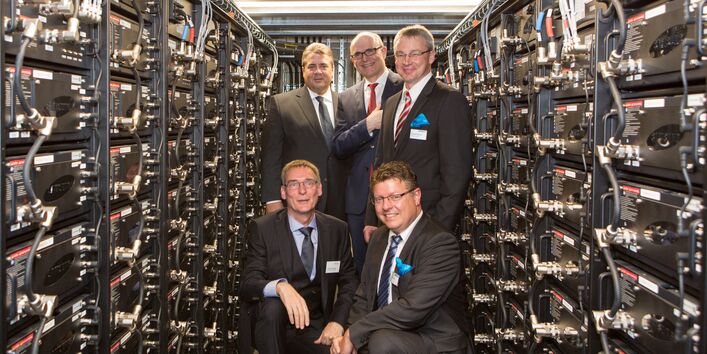 5 Männer in Anzügen und Krawatte in einem engen Technikraum