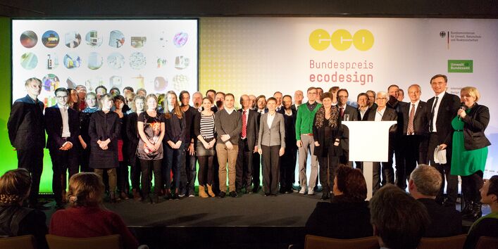 Vor einer Stellwand mit dem Logo des Bundespreis Ecodesign stehen die Preisträger