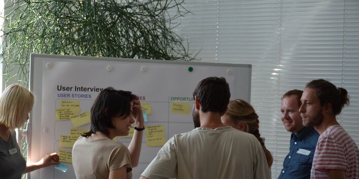 Teilnehmerinnen und Teilnehmer eines Workshops vor einem Flipchart