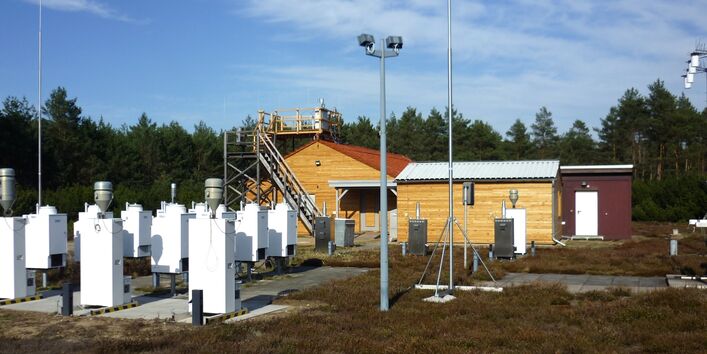 Outdoor observation area, two small buildings of light-coloured wood in the background