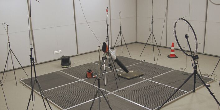 in einem unmöblierten Raum steht in der Mitte eine Haltevorrichtung und darum auf Ständern viele Spezialmikrofone