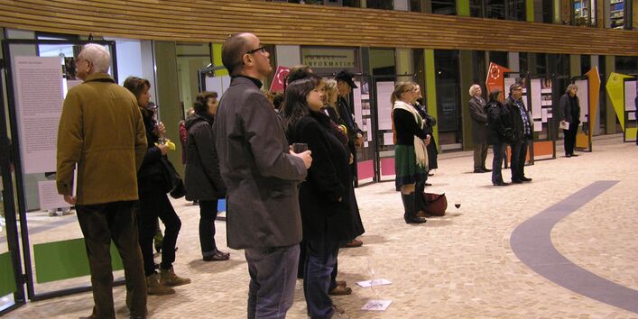 Mehrere Personen schauen sich die Austellung (Schautafeln) im Atrium des Umweltbundesamtes in Dessau an.