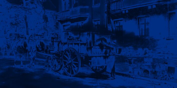 Ein Arbeiter entleert einen Eimer au offene Ladefläche eines Pferdewagens.