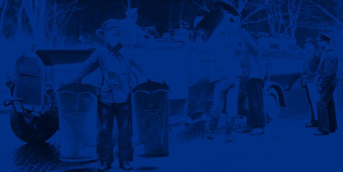 Mehrere Arbeiter entleeren Eimer in ein Müllfahrzeug