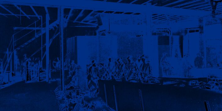 Mehrere Arbeiter sortieren Abfall von Hand, sie stehen an einem langen Tish