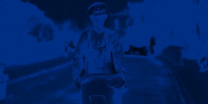 Ein Mann trägt eine hohe Mülltonne auf der Straße