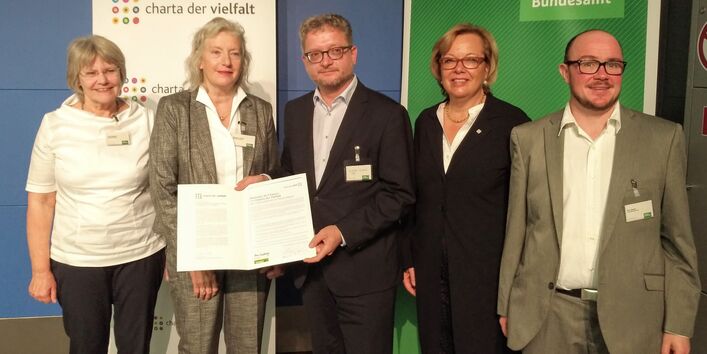 Fünf Personen mit der unterzeichneten Charta der Vielfalt.