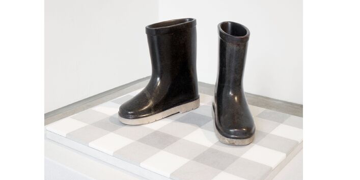 schwarze Plastikstiefel auf einem weißen Podest