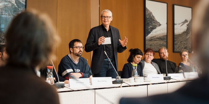 Ein Herr im dunklen Anzug steht und spricht