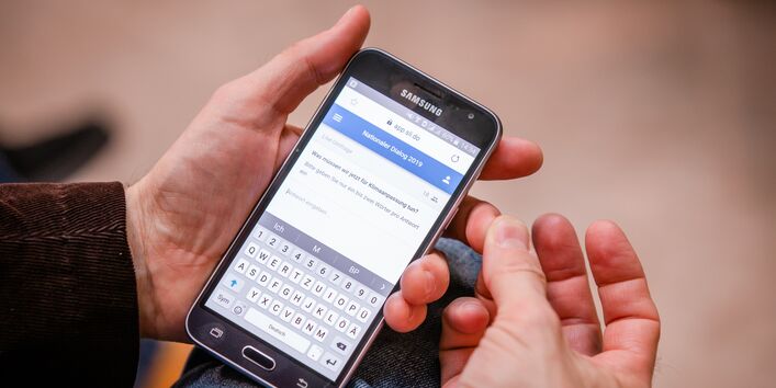 Ein Teilnehmer zeigt auf seinem Smartphone die digitale Befragung: Was müssen wir jetzt für den Klimawandel tun ?