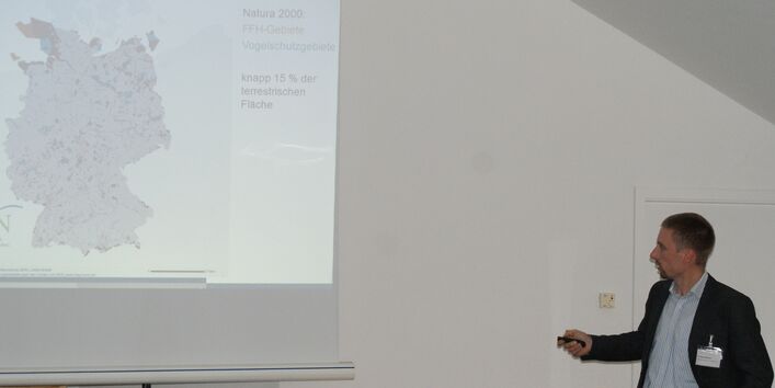 Teilnehmer trägt vor zu Vogelschutzgebieten und zeigt mit dem Pointer in der Hand auf die Deutschlandkarte.