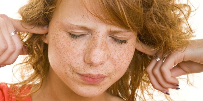 Rothaariges Mädchen hält sich die Ohren zu