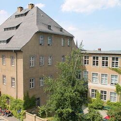 Fassade des Museums im Vordergrund eine Straße, vor dem Gebäude steht eine Gruppe von Menschen