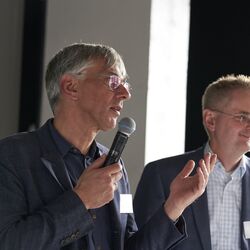 Das Foto zeigt Stefan Tidow (BMUV) mit Mikrofon und Martin Schmied (UBA) bei der Begrüßung der Teilnehmenden.