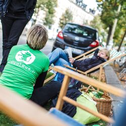 Menschen rasten auf Parkplatz an Straßenrand mit Sonnenliegen
