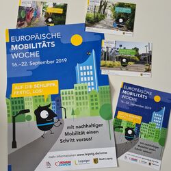 Plakate und Flyer der Fotoaktion in Leipzig "Auf die Schlippe, fertig, los!" und ein Flyer in Blindenschrift