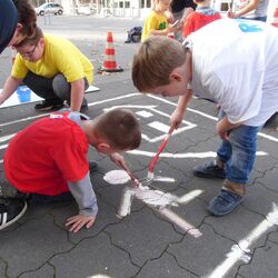 Kinder malen ihr Verkehrszeichen auf den Boden