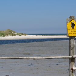 Schild mit Beschriftung „Nationalpark Kernzone“ vor Küstenlandschaft.