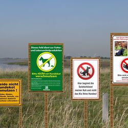 Vier verschiedene Hinweisschilder vor einer Weide, welche Hundebesitzer (teils humorvoll) über das Risikopotential von Hundekot auf Weiden hinweisen
