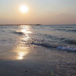Sandstrand mit Brücke im Hintergrund. 