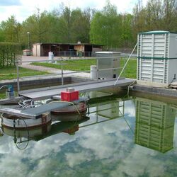 Wasserfläche mit Versuchsaufbauten im Freien.
