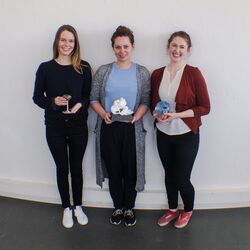 drei junge Frauen mit Trophäen lehnen an einer Wand