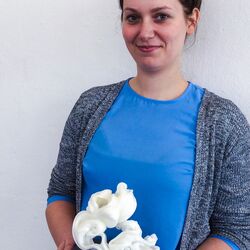 junge Frau mit einer Trophäe in der Hand, ein weißes, filigranes Gebilde auf einem Sockel