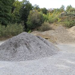 Im Vordergrund ein Haufen kleiner grauer Steine, im Hintergrund ein Haufen kleiner gelblicher Steine
