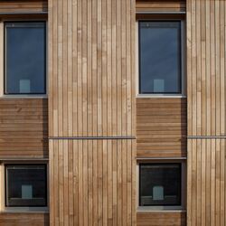Fassade mit Holztafeln verkleidet, die Holztafeln bilden ein Raster aus größeren senkrechten Tafeln mit senkrechten Holzlatten und kleineren waagerechten Tafeln mit waagerechten Holzlatten