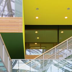 Skywalks and stairs with glass banisters in inner courtyard, inner façade of wood, yellow and green surfaces