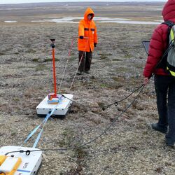 Zwei Forscherinnen stehen mit ihren Instrumenten in der arktischen Landschaft.