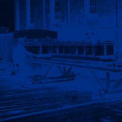 Zwei Männer tauschen Eimer auf einem auf Schienen laufenden Wagen aus.