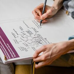 Sie sehen ein Bild aus dem Nationaler Dialog 2019: Klimawandelfolgen in Deutschland – Bereit zu handeln für bessere Vorsorge. Zusehen ist ein Blatt Papier, auf dem eine Person eine Vision malt, skizziert. Man sieht allerdings nur die Händer der Person. 